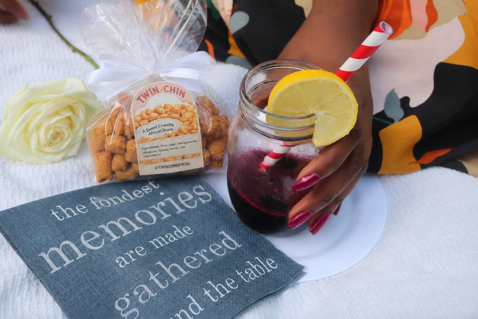 A hand holding a mason jar of homemade Zobo drink with lemon, paired with TwinChin chin chin